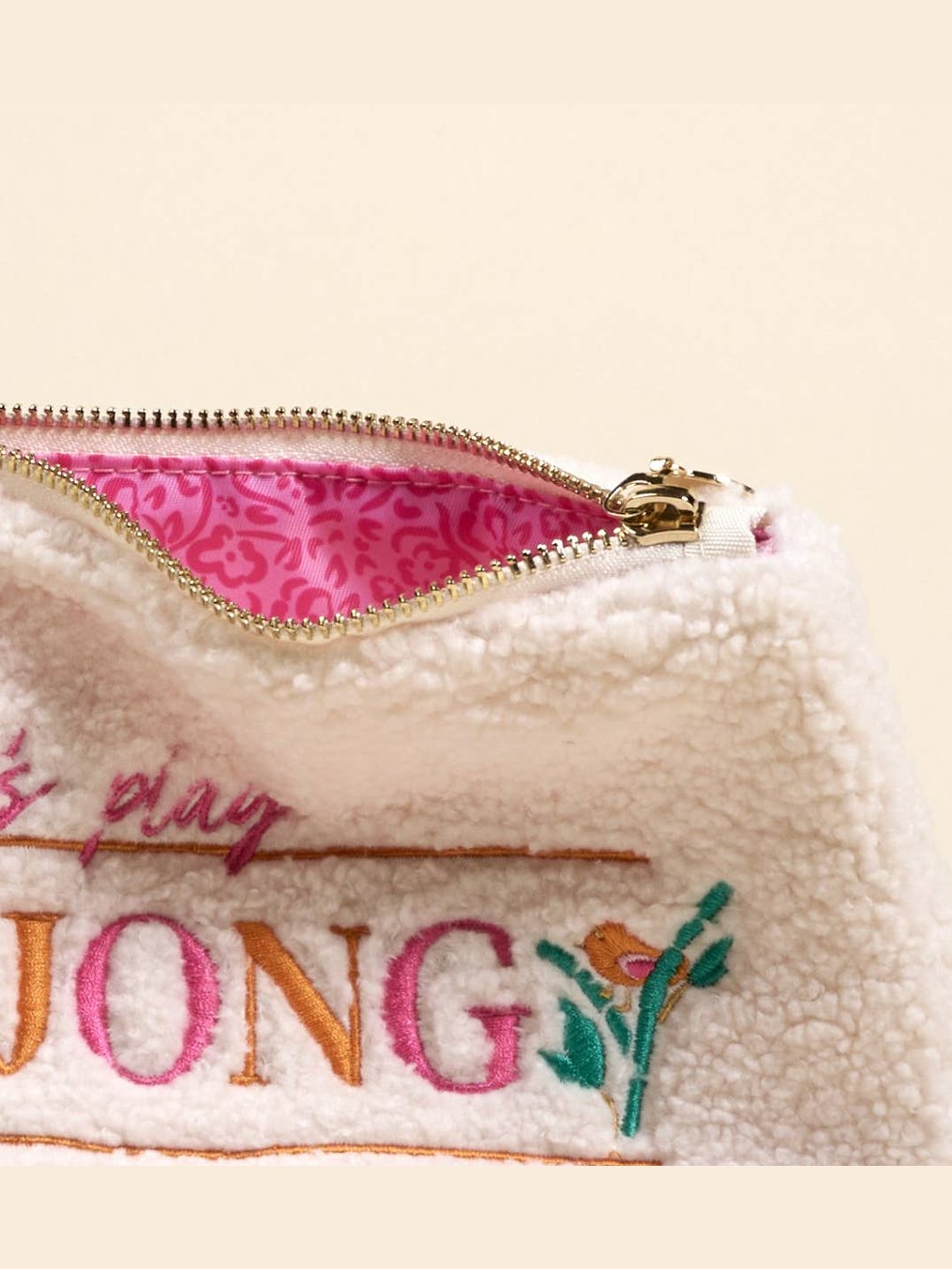 Close-up of cream sherpa pouch showing pink patterned interior lining