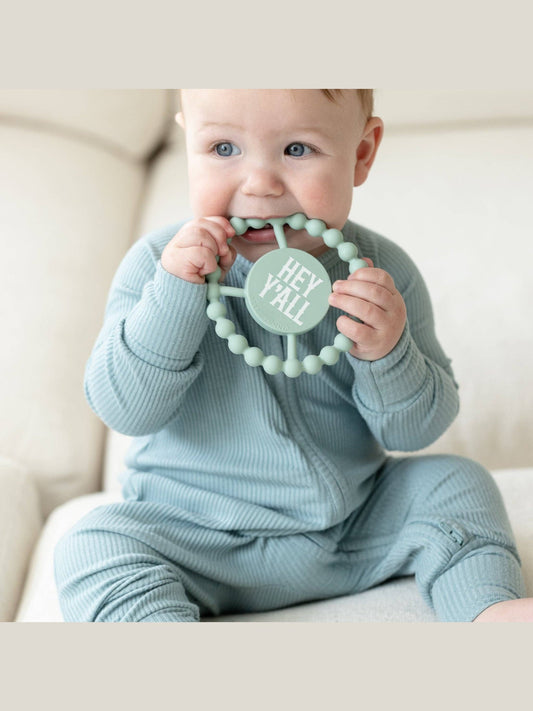Baby holding sage green Hey Yall Happy Teether ring