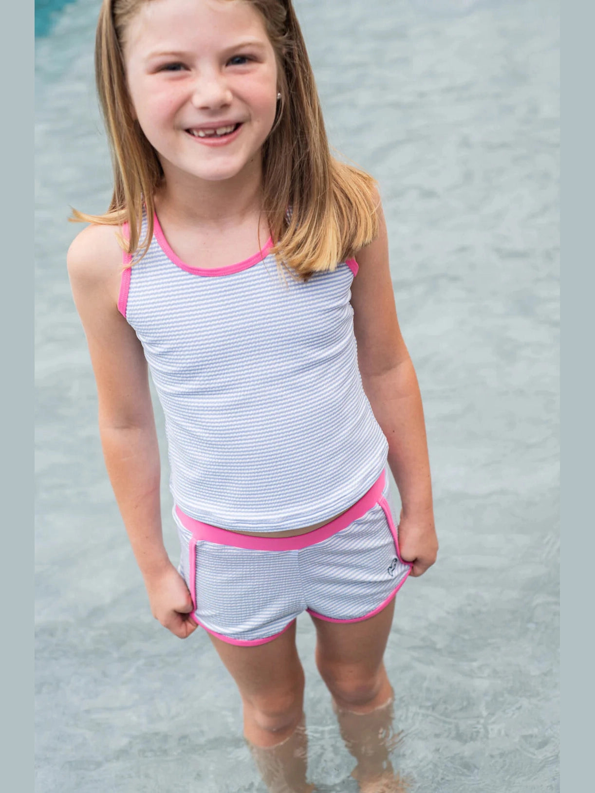 Girl wearing UPF 50 blue striped tankini set in shallow water