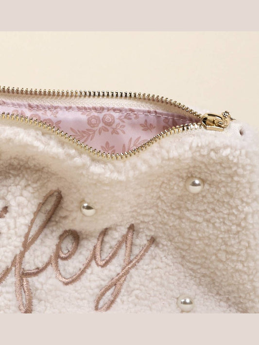 Close-up of floral pink lining inside cream teddy pouch with gold zipper