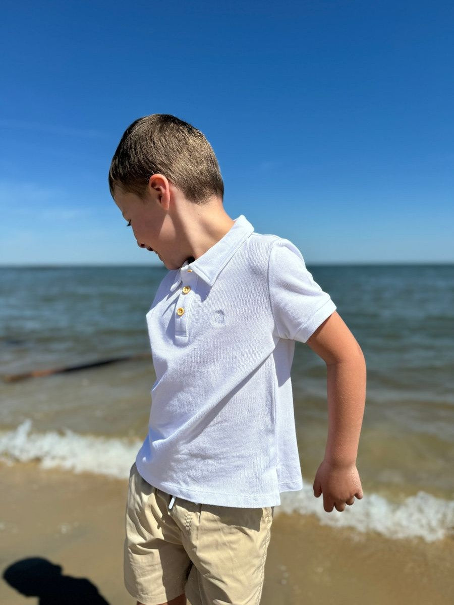 Close-up of white pique polo texture and tan buttons on boy